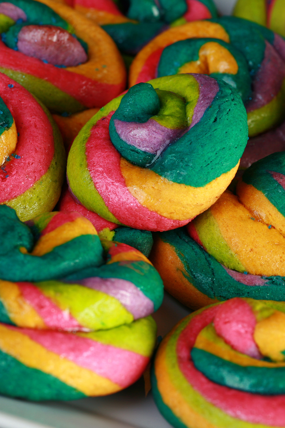 A close up view of a pile of gluten-free unicorn poop cookies. They are brightly coloured cookie "poops" made from brightly coloured twists of cookie dough.