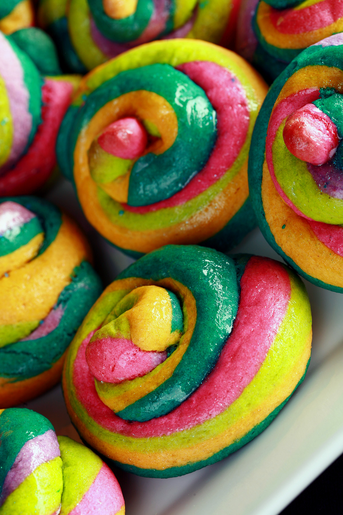 A close up view of a pile of gluten-free unicorn poop cookies. They are brightly coloured cookie "poops" made from brightly coloured twists of cookie dough.
