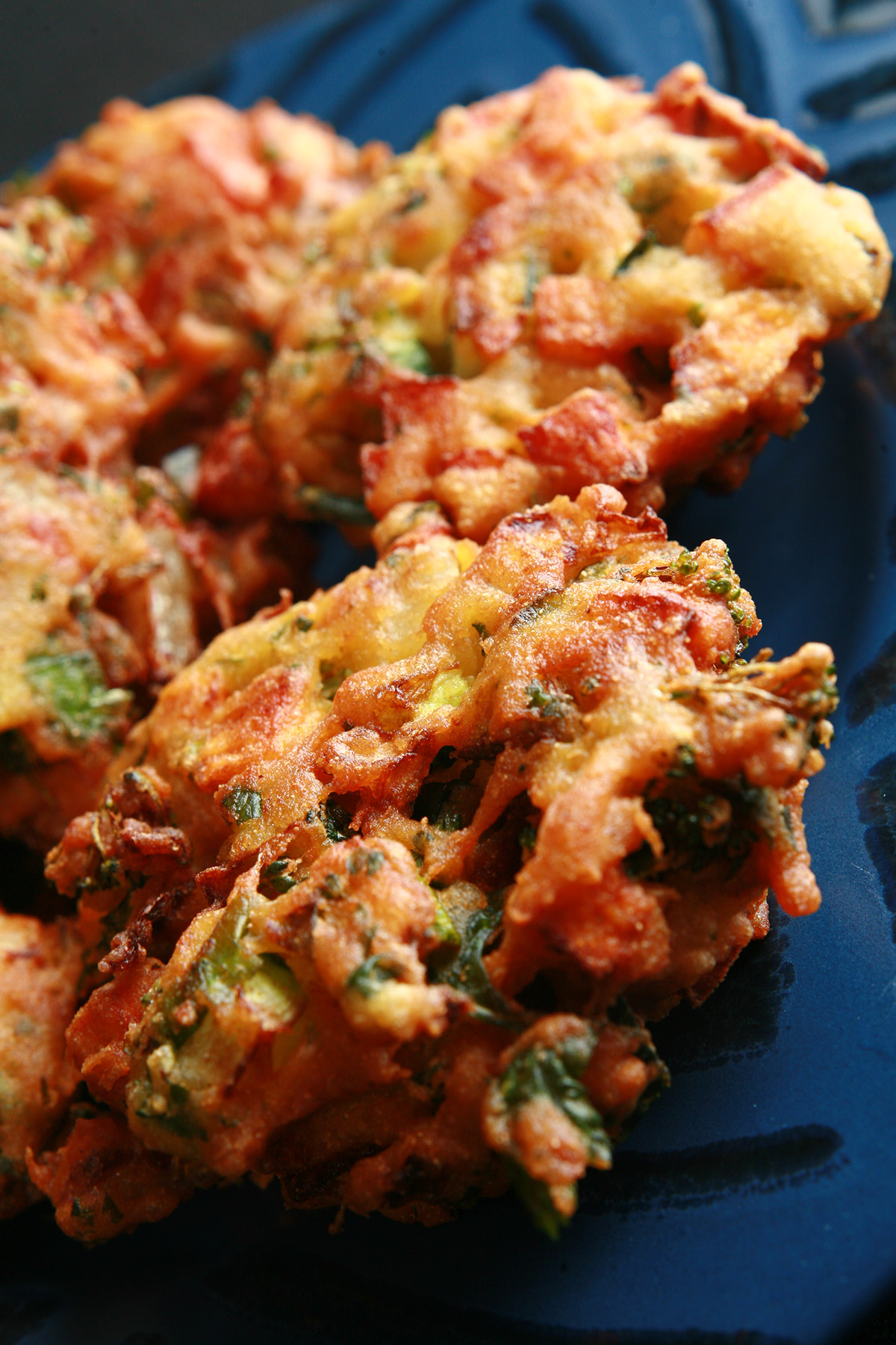 Several Mixed veggie pakora, on a blue plate.