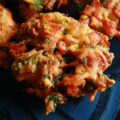 Several Mixed vegetable pakora, on a blue plate.