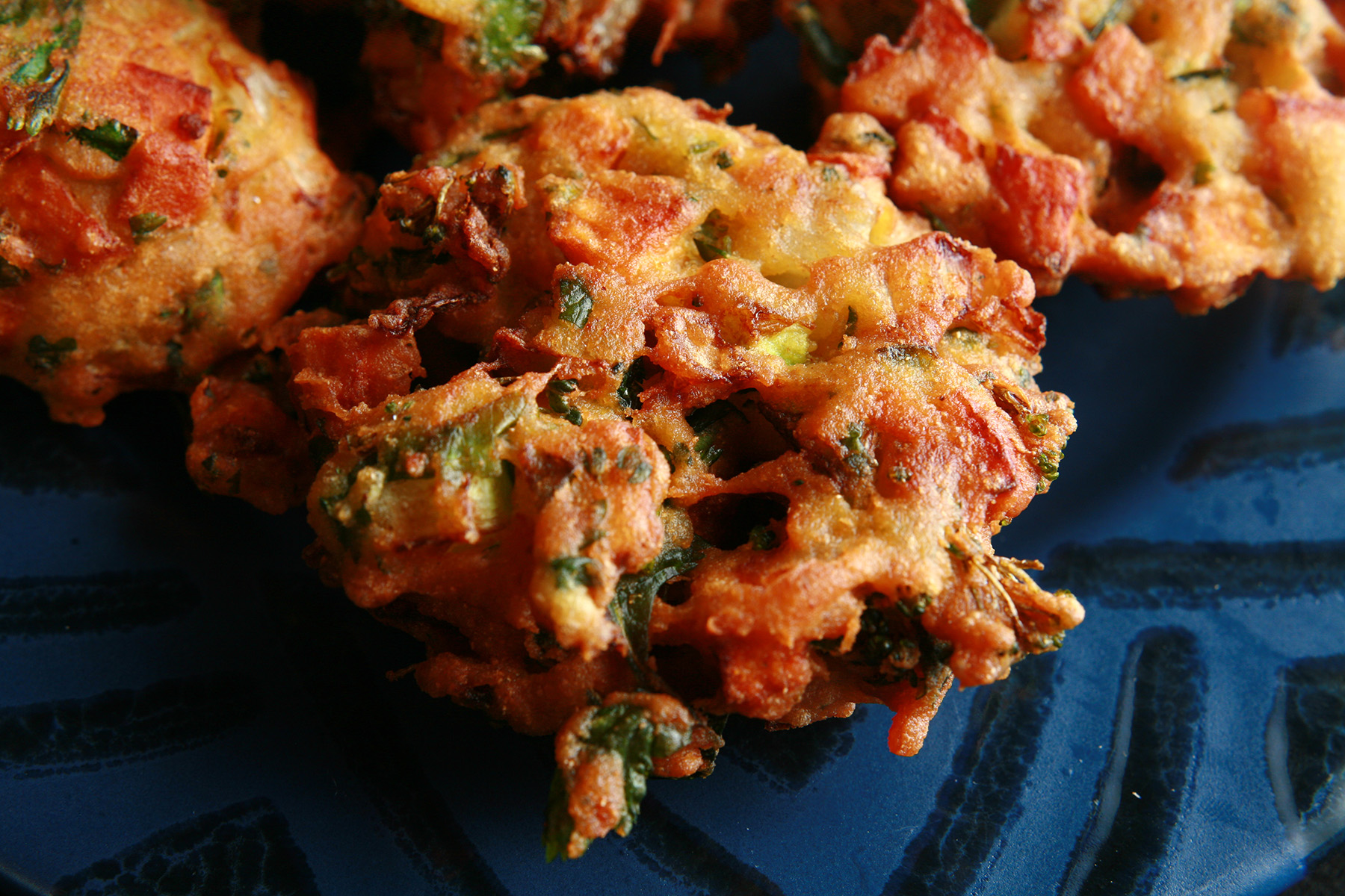 Several Mixed vegetable pakora, on a blue plate.