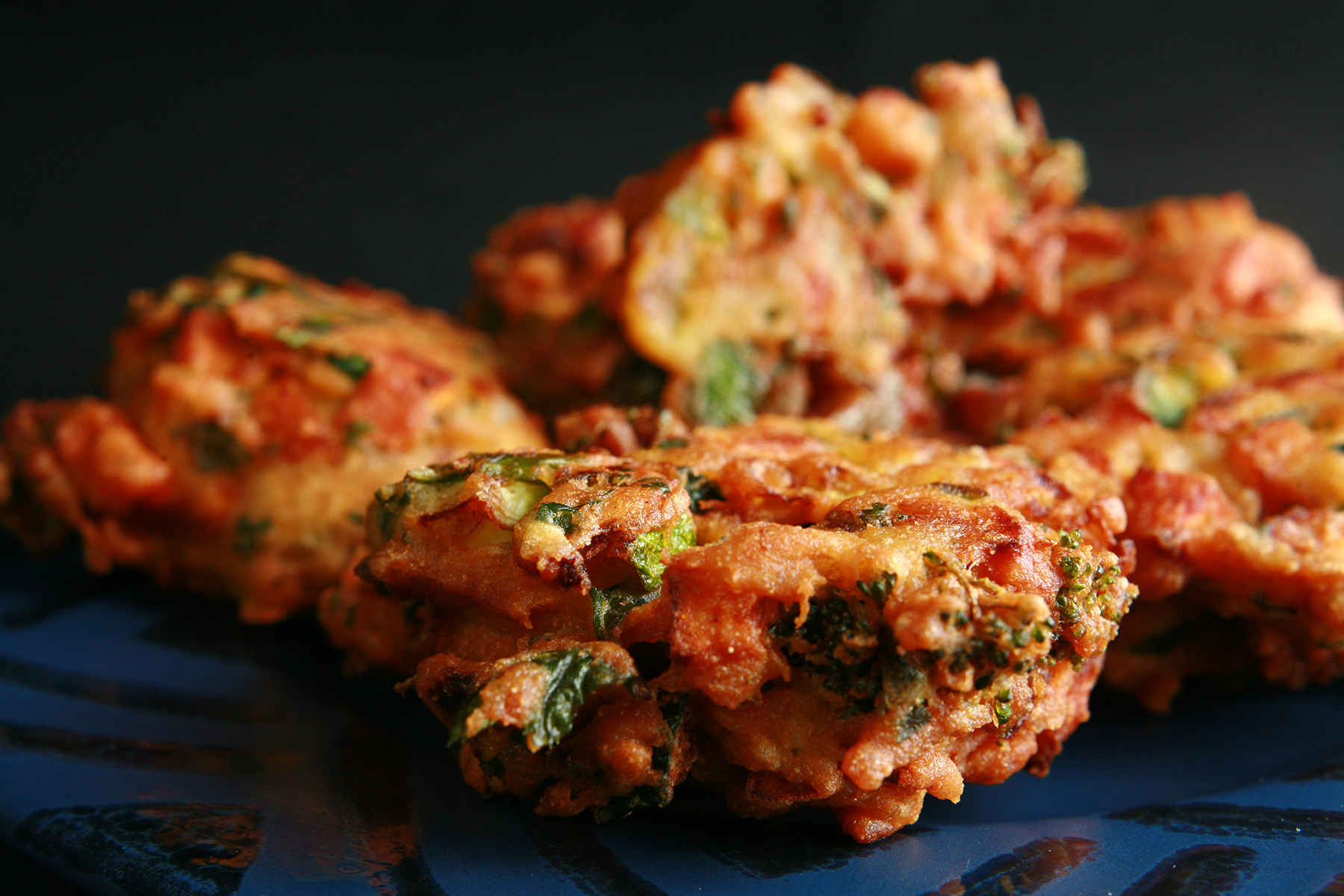 Several Mixed vegetable pakora, on a blue plate.