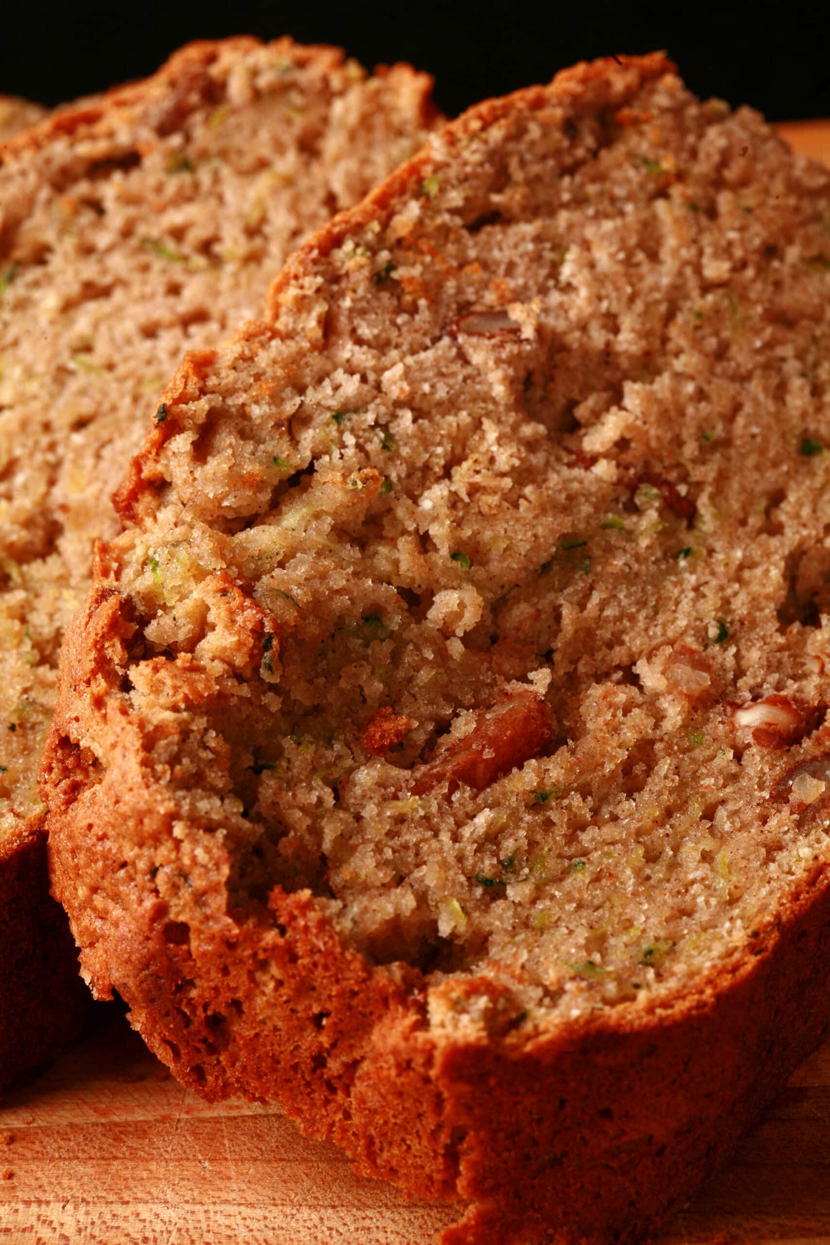 A sliced loaf of gluten-free zucchini bread on a wooden cutting board.