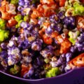 A bowl of Halloween popcorn - orange, purple, and lime green glazed popcorn, mixed together.