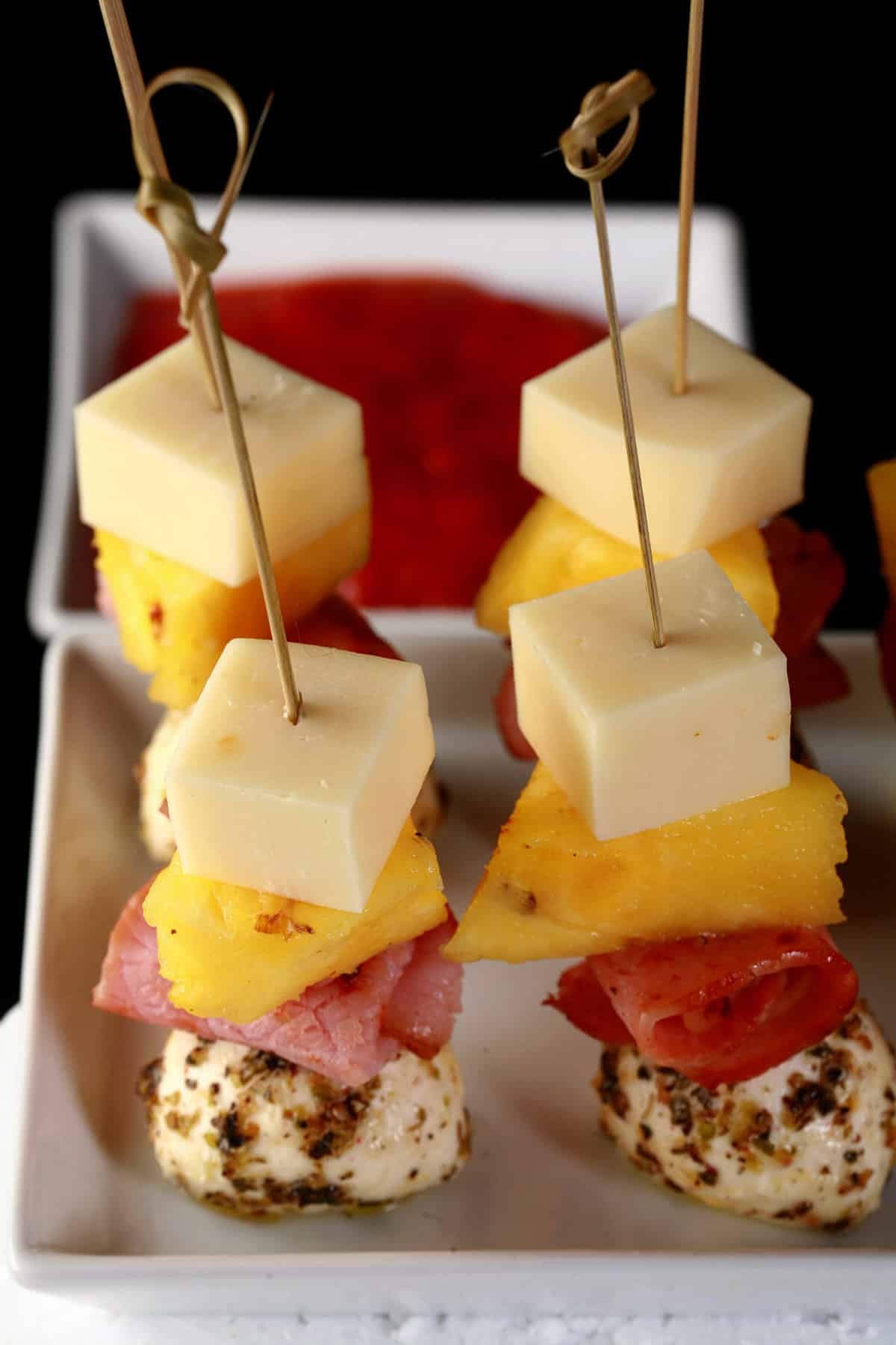 A tray of hawaiian pizza skewers - pineapple, back bacon, and 2 kinds of cheese.