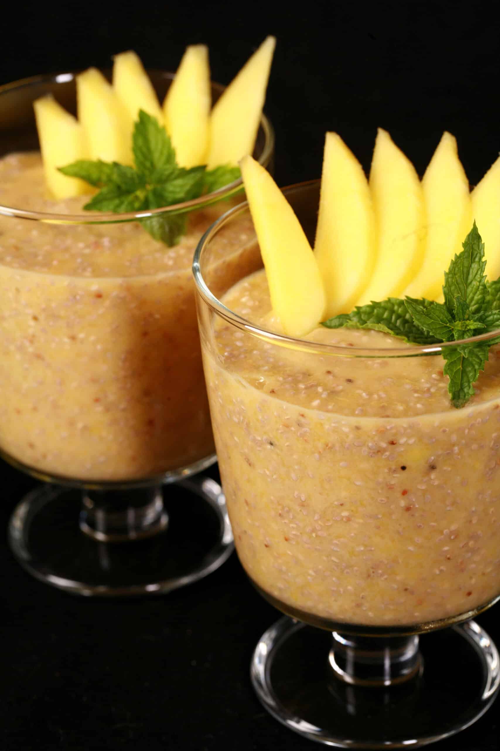 2 glasses of mango chia seed pudding, garnished with mango slices and fresh mint leaves.