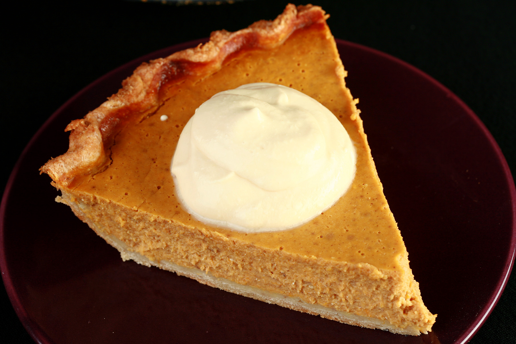 A slice of pumpkin pie with maple cream.