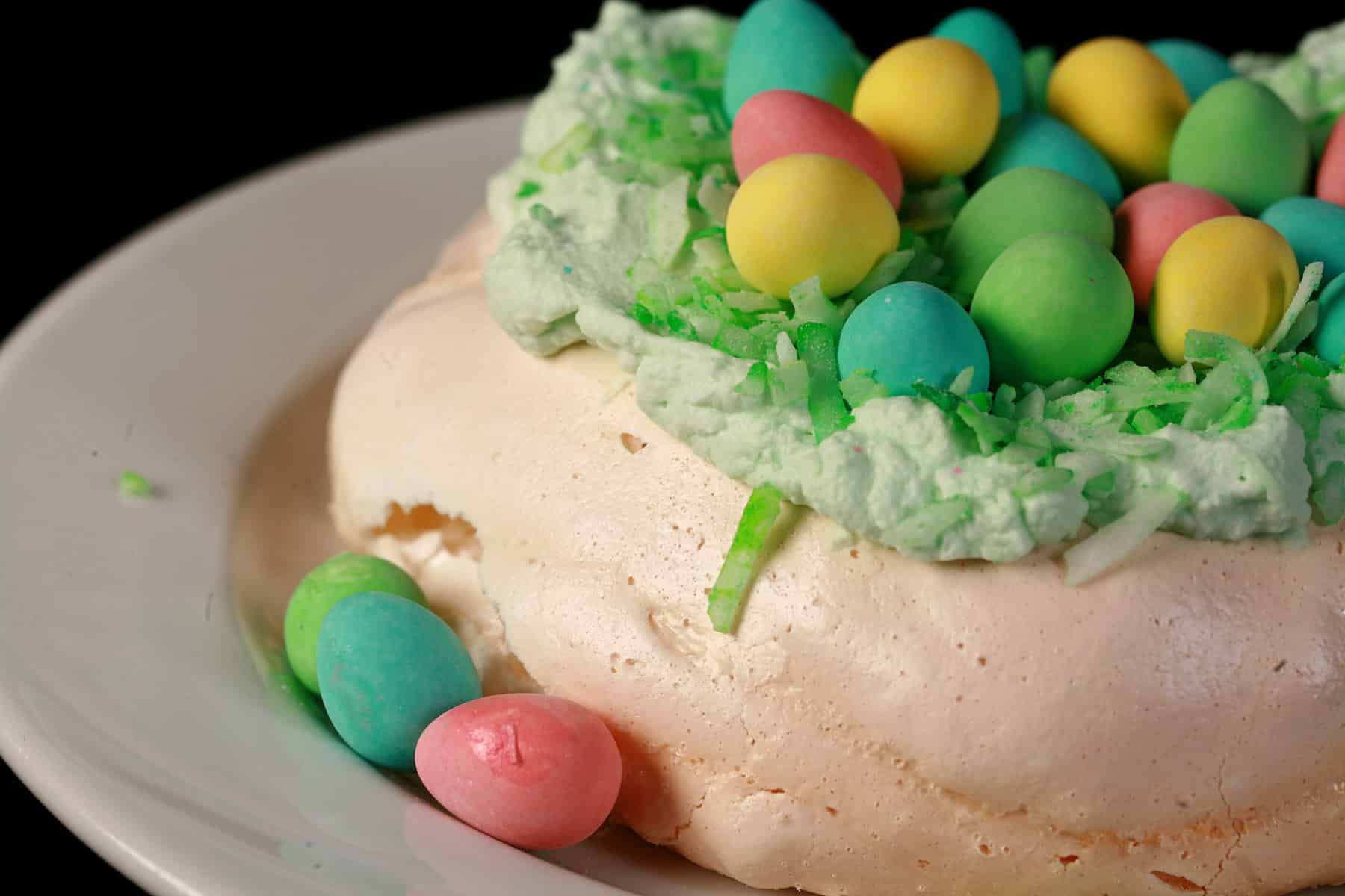 A single mini Easter pavlova, topped with green coconut and cadbury mini eggs.