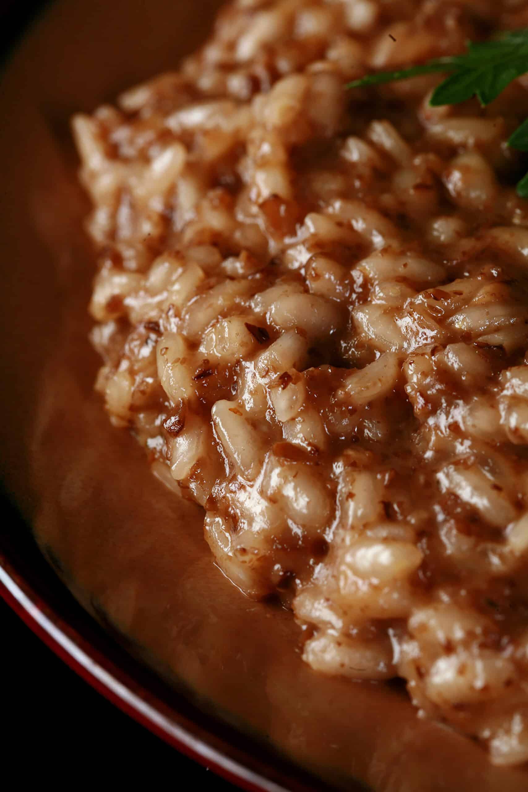 A plate of creamy mushroom risotto, garnished with parsley leaves and sliced mushrooms.