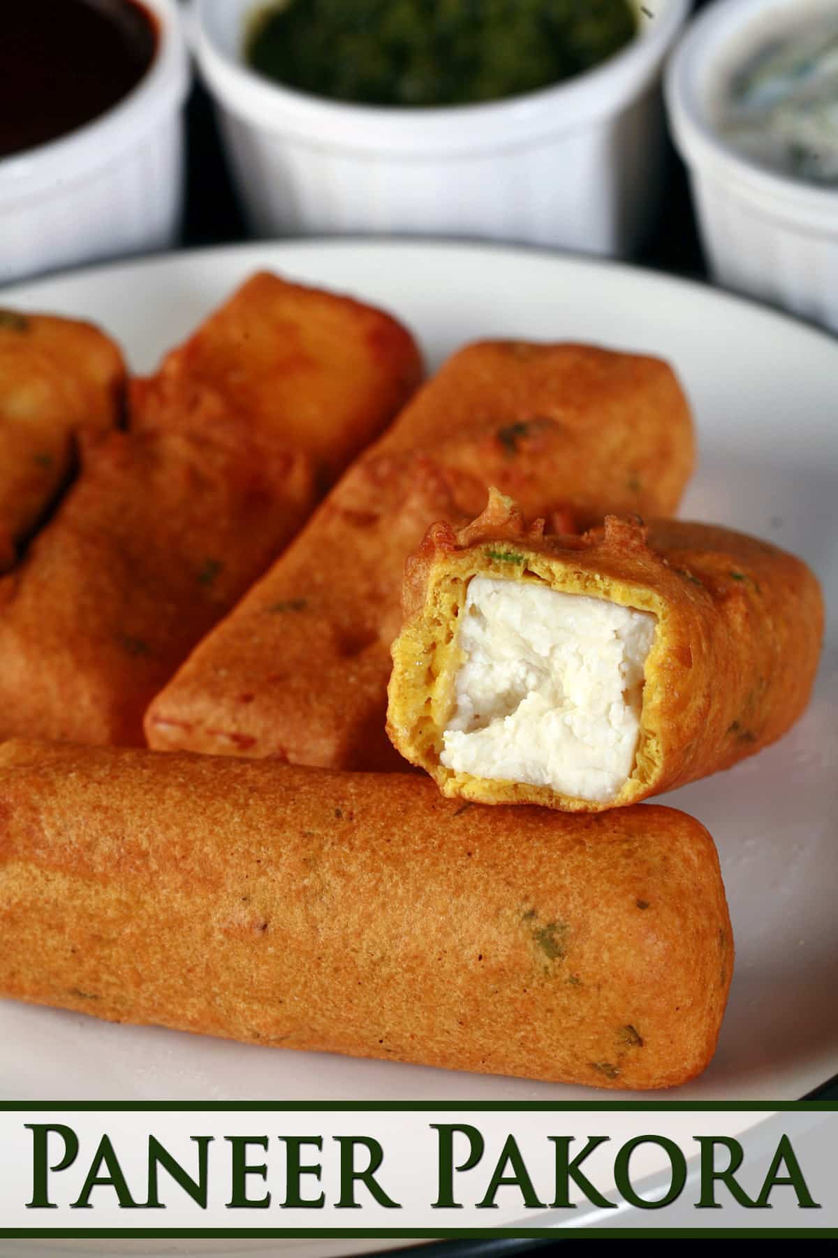 A plate of paneer pakora, with one bitten in half.