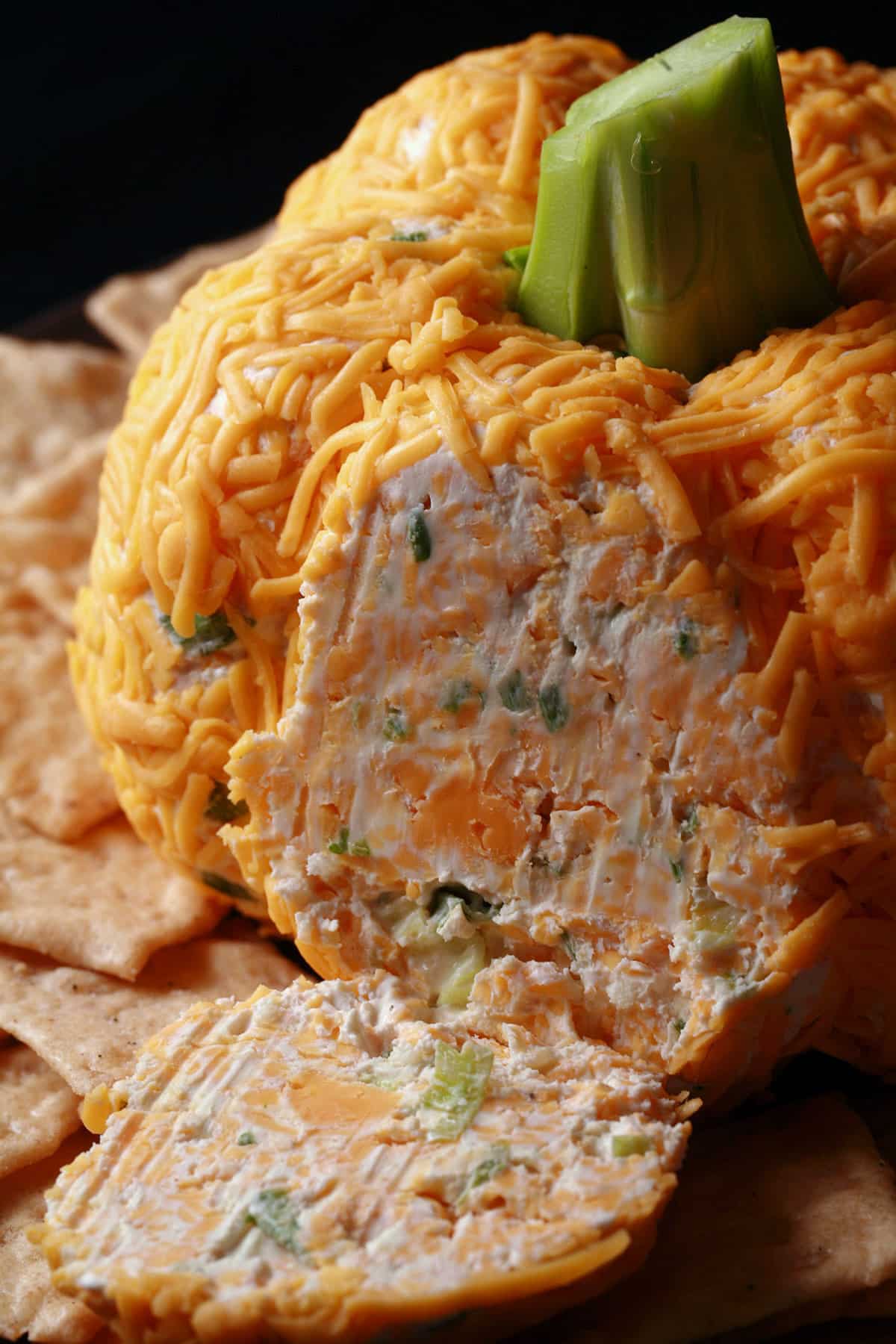A pumpkin shaped cheese ball with green onion visible inside.