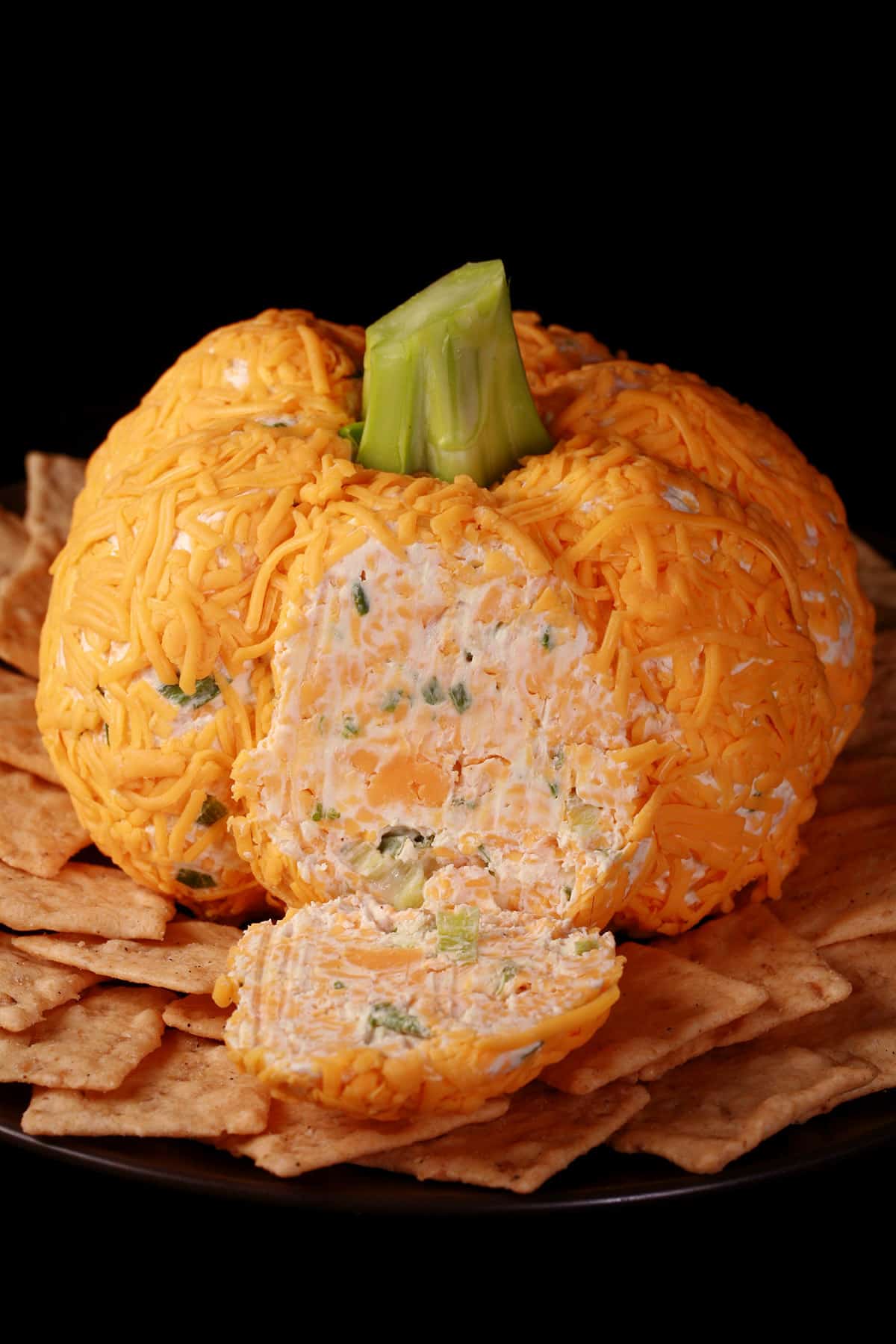 A pumpkin shaped cheese ball with green onion visible inside.