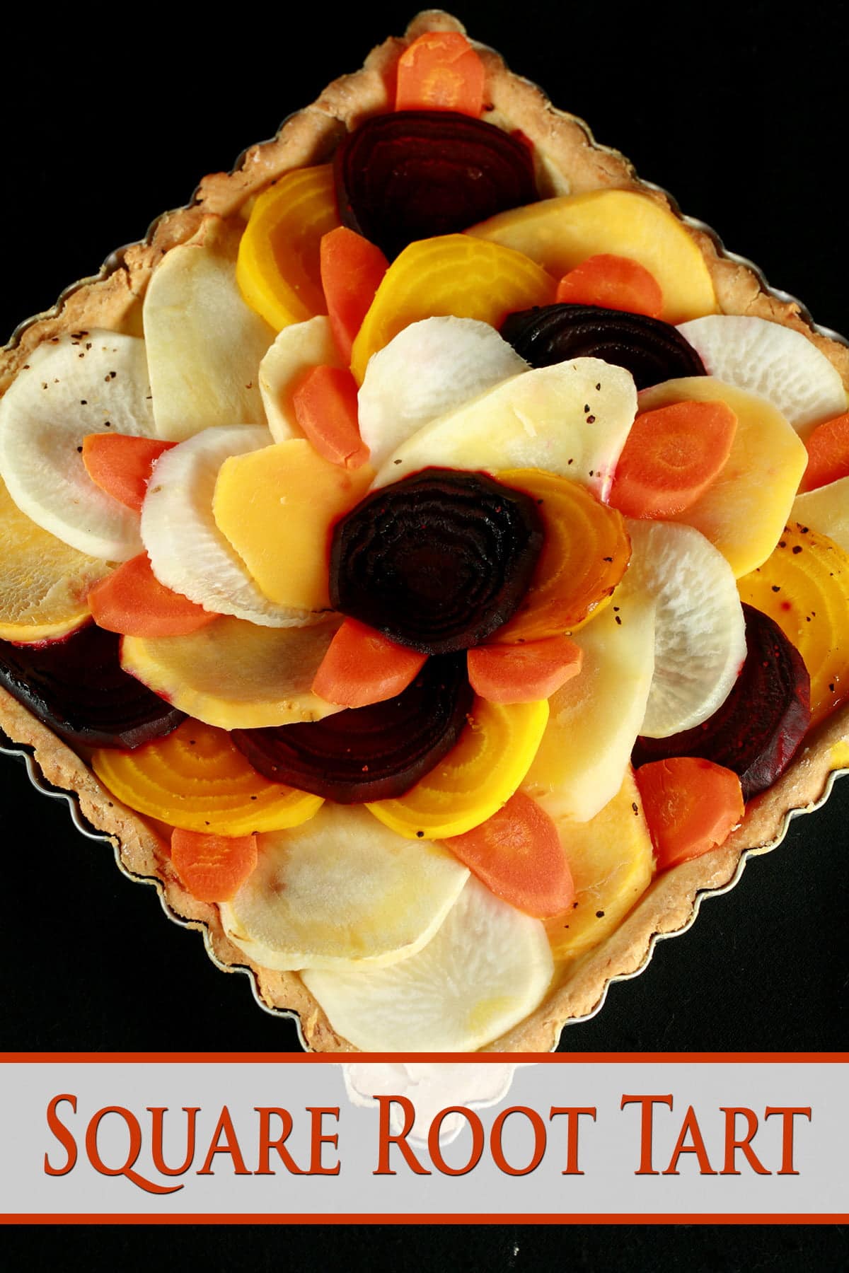 A close up view of a square root tart - a tart cooked in a square pan, with slices of a variety of root veggies arranged on top.