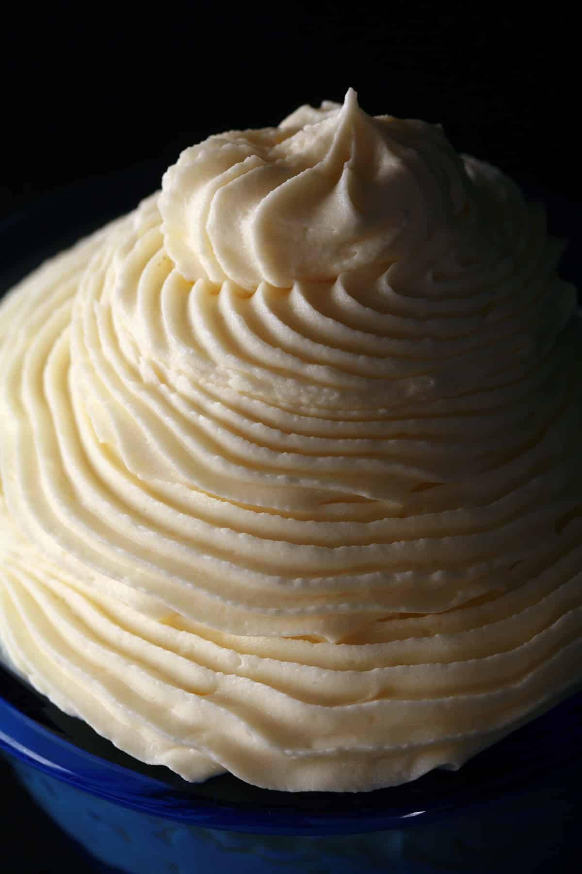 A tall swirl of white chocolate whipped ganache in a small bowl.