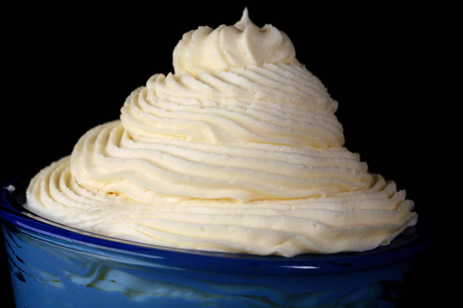 A tall swirl of white chocolate whipped ganache in a small bowl.